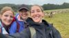 Selfie von drei Media Solutions Mitarbeiterinnen die in die Kamera lächeln. Im Hintergrund sind Schafe zu sehen